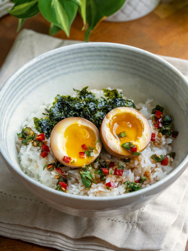 Jammy Korean marinated eggs (mayak eggs) in a bowl with rice.