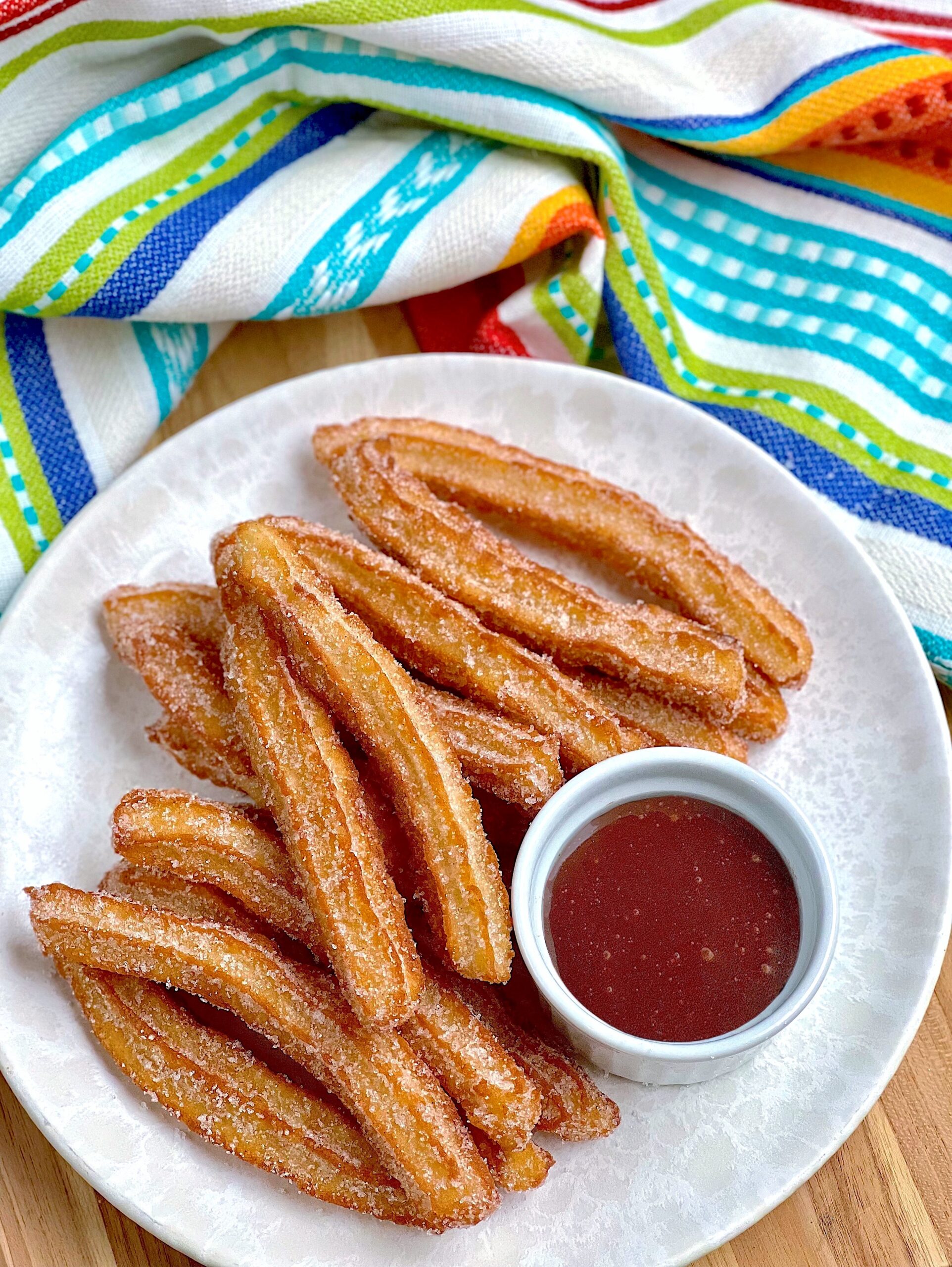 A plate of churros fresh out the fryer coated in cinnamon and sugar