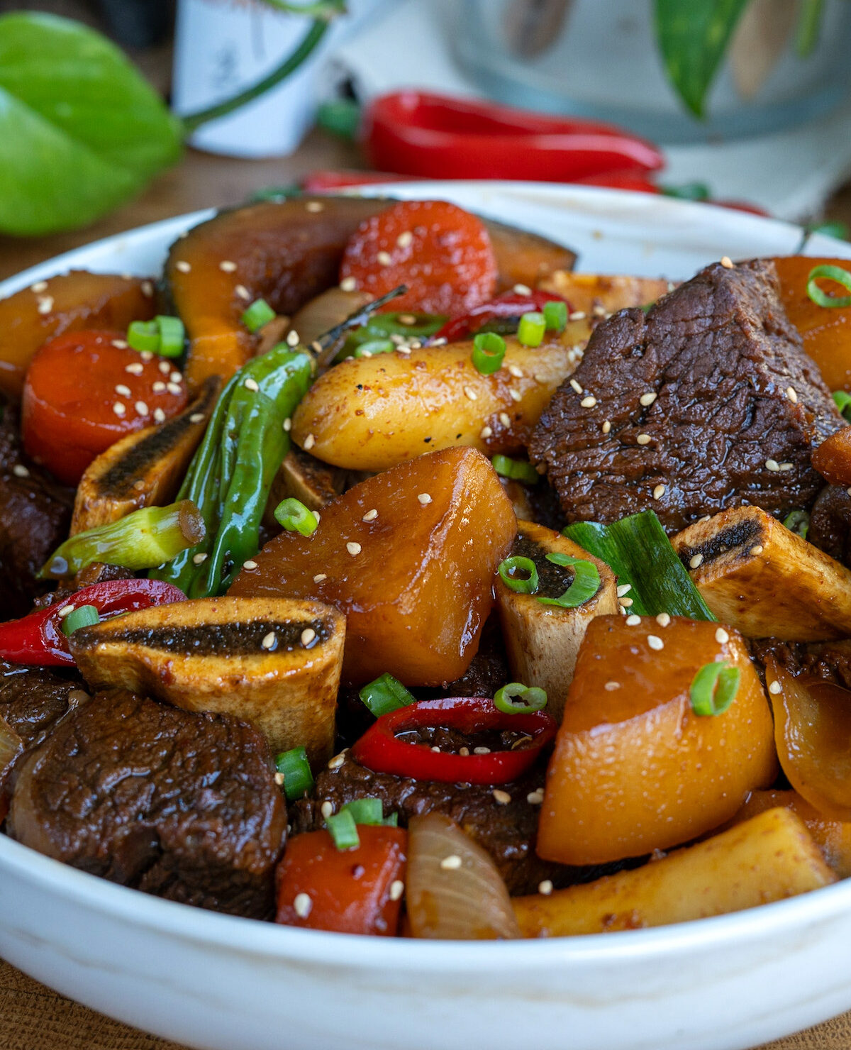 a bowl of galbi jjim (koran braised short ribs) with korean radish, peppers, carrots, and rice cake.