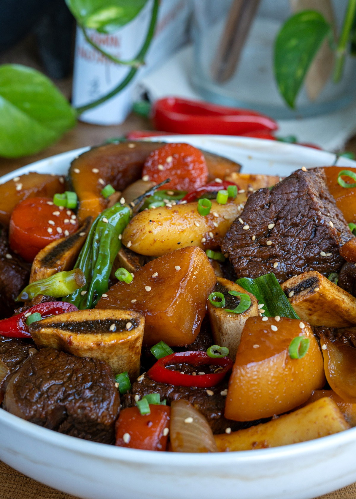 a bowl of galbi jjim (koran braised short ribs) with korean radish, peppers, carrots, and rice cake.