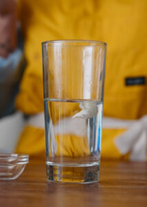 A glass of water with a dollop of masa (corn dough) floating at the top