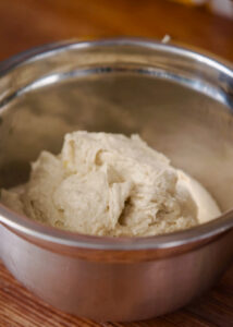 A stainless steel bowl filled with masa that is resting before making tamales.