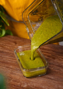 Some salsa verde being poured into a container to reserve for later.