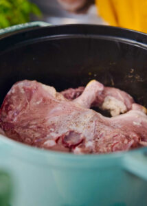 Raw spatchcocked chicken seasoned with salt and pepper being seared in a pot, skin side down.