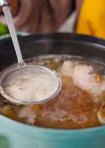 Skimming impurities off of boiling chicken.