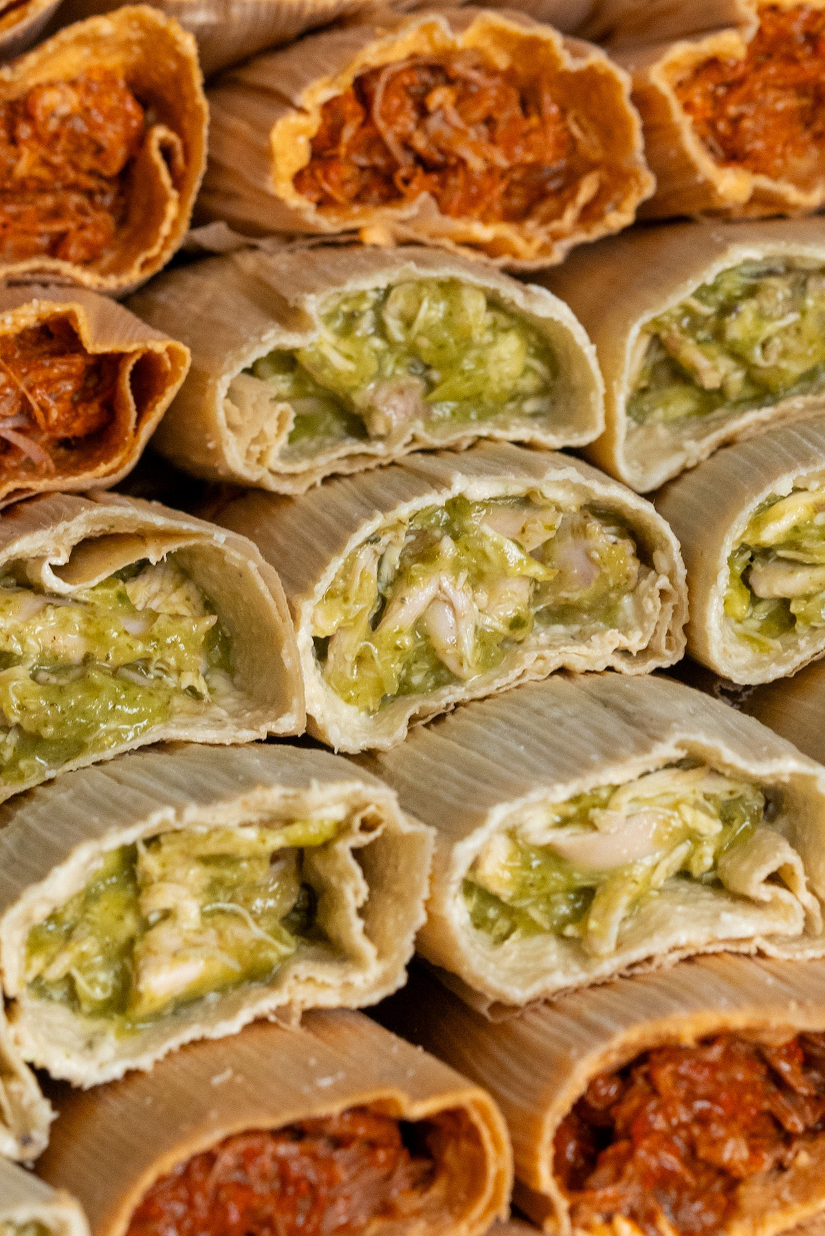 variety of tamales with different fillings, stacked and ready to be steamed or frozen.