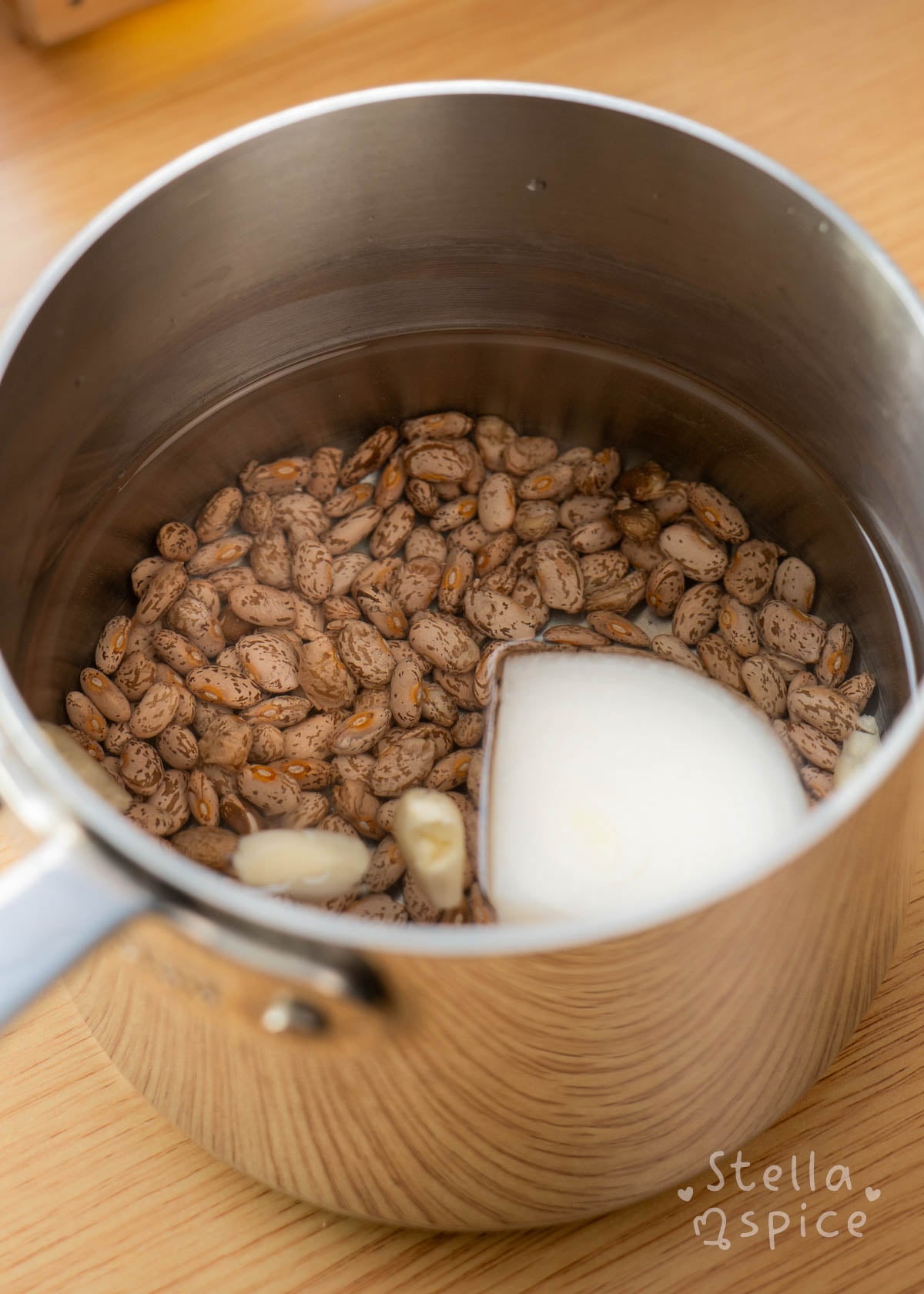 pinto beans in a pot with onion, garlic, and salt